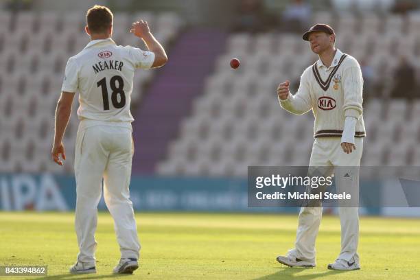 Surrey captain Gareth Batty tosses the ball to Stuart Meaker during day two of the Specsavers County Championship Division One match between...