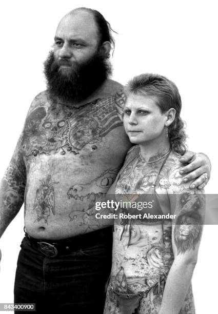 Heavily-tattooed man and woman pose for photographs in Daytona Beach, Florida, during the city's 1983 Bike Week. The annual motorcycle event and...