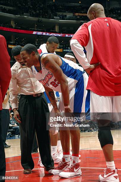 Marcus Camby of the Los Angeles Clippers grimaces while being tended to by head athletic trainer Jasen Powell during a game against the Milwaukee...
