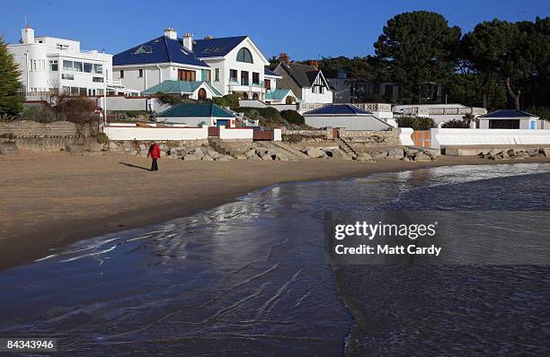 People walk on the beach in the exclusive residential area of Sandbanks on January 17 in Poole, England. Before the credit crunch properties built on...