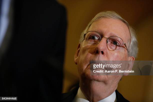 Senate Majority Leader Mitch McConnell looks on as Sen. John Cornyn speaks with reporters following the weekly Senate Republican policy luncheon at...