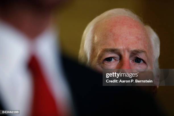 Sen. John Cornyn looks on as Sen. John Barrasso speaks with reporters following the weekly Senate Republican policy luncheon at the U.S. Capitol...