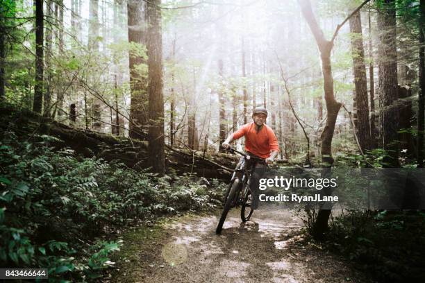 reifer mann mountainbiken im wald - pacific northwest stock-fotos und bilder