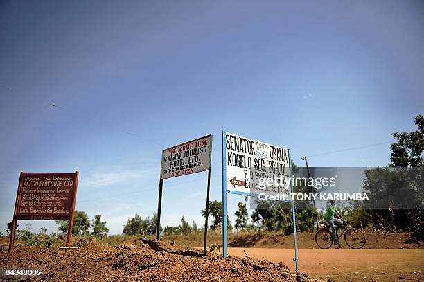 Photo taken January 13, 2009 shows a villager of Nyang'oma, in Kogelo riding past road signs advertising a tourist hotel and information centre...