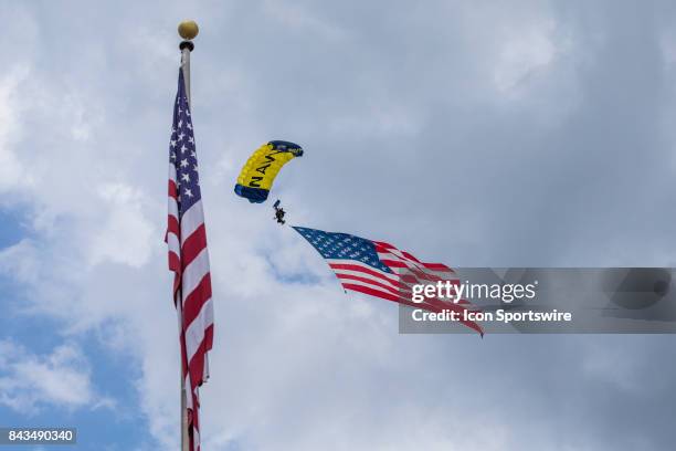 Member of the Leap Frogs, the U.S. Navy parachute demonstration team, delivers the American flag during the national anthem prior to the start of the...