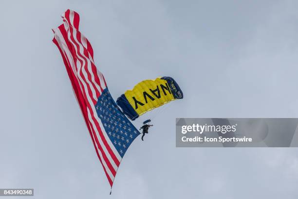 Member of the Leap Frogs, the U.S. Navy parachute demonstration team, delivers the American flag during the national anthem prior to the start of the...