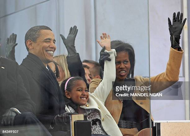 President-elect Barack Obama, his wife Michelle and their daughter Sasha raise their hands during the song "Shout" performed by Garth Brooks at the...