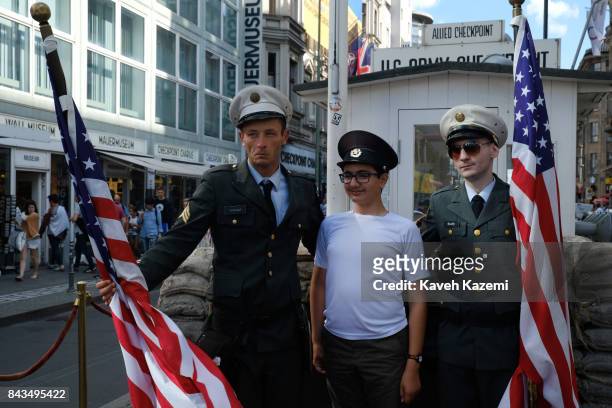 Fake U.S. Military men wearing uniforms hold American flags take a souvenir photo with a young tourist boy in exchange for a tip at Checkpoint...