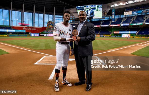 Dee Gordon of the Miami Marlins receives the Roberto Clemente nominee trophy from president of baseball operations Michael Hill before the game...