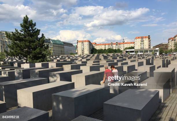 Couple sit on a concrete slabs or "stelae" in The Memorial to the Murdered Jews of Europe, also known as the Holocaust Memorial designed by architect...
