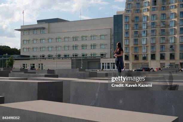 Woman stands lon a concrete slabs or "stelae" in The Memorial to the Murdered Jews of Europe, also known as the Holocaust Memorial designed by...