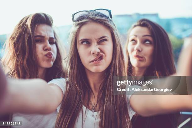 group of crazy girls taking selfie and making faces outdoors - blonde girl sticking out her tongue stock pictures, royalty-free photos & images