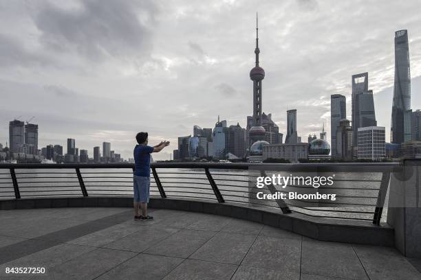 Woman exercising on the bund looks across the Huangpu River to the Lujiazui Financial District in Shanghai, China, on Monday, Sept. 4, 2017. The...