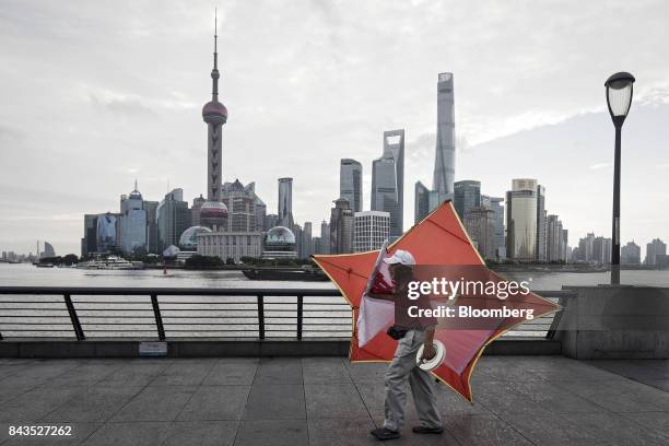 Man carries a kite along the bund as the Lujiazui Financial District stands in the background in Shanghai, China, on Monday, Sept. 4, 2017. The...