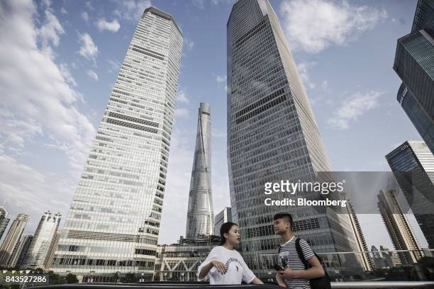 Pedestrians stand on an elevated walkway as the Shanghai Tower, center, stands in the background in the Lujiazui Financial District in Shanghai,...