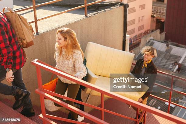 happy female climbing steps with males on building. high angle view of multi-ethnic friends are carrying sofa while moving towards terrace. they are wearing casuals. - carrying sofa stock pictures, royalty-free photos & images