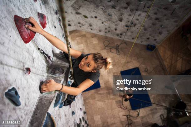 above view of young woman exercising wall climbing in a gym. - climbing help stock pictures, royalty-free photos & images