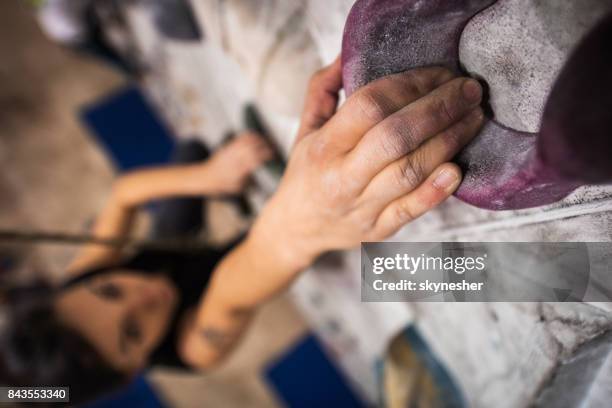 close up of a climber's hand on a climbing wall in a gym. - climbing wall stock pictures, royalty-free photos & images