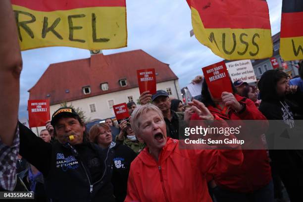 Protesters and hecklers chant "Merkel muss weg!" and "Volksverraeter!" while holding up red slips of paper that read: "Red card for Merkel!" at the...
