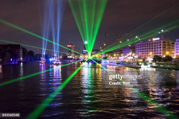 public light event in berlin - light beams at the berlin skyline with landmarks molecule men, oberbaumbrücke and televisiontower (berlin, germany) - friedrichshain - fotografias e filmes do acervo