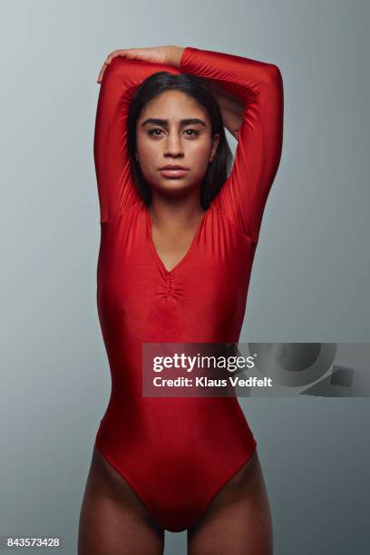 Female gymnast stretching and looking in camera, wearing leotard