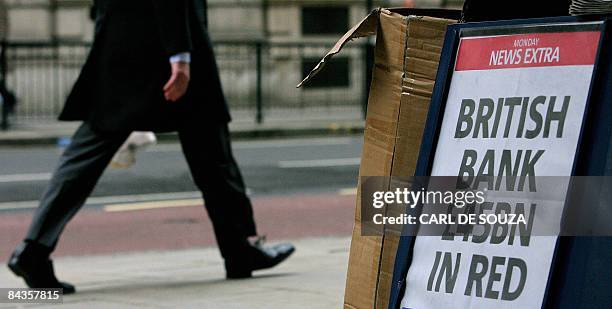City worker walks past a newspaper headline billboard in central London, on January 19, 2009. Britain unveiled a second bank rescue package worth...