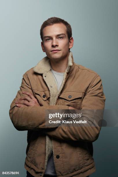 young man with crossed arms looking in camera - beige jacket ストックフォトと画像