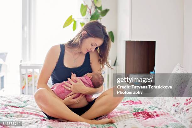 young mother breastfeeds her baby, holding him in her arms and smiling from happiness - chest imagens e fotografias de stock