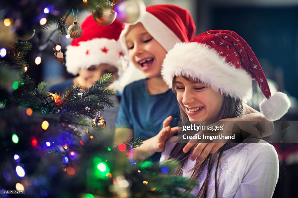 Kinder schmücken Weihnachtsbaum