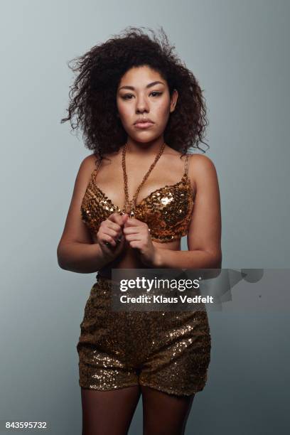 Cool young woman wearing gold party clothes, looking in camera