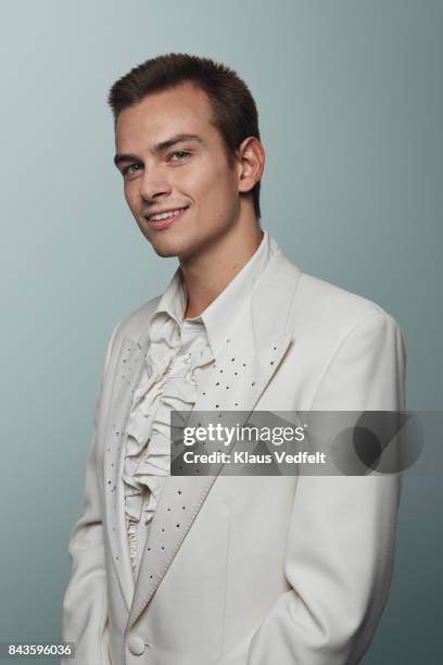 young man wearing 70' white suit and puffy shirt, smiling to camera - shirt met ruches stockfoto's en -beelden