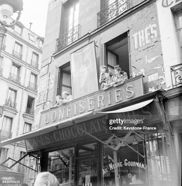 Des Parisiens aux fenêtres regardent le défilé des Ecossais, à Paris, France en 1946.