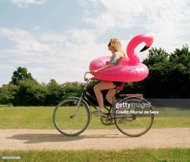 young woman cycling with flamingo ring - good times stock pictures, royalty-free photos & images