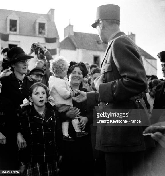 Le général de Gaulle serre la main d'un bébé dans les bras de sa mère venue l'accueillir, Ile de Sein, France en septembre 1946.