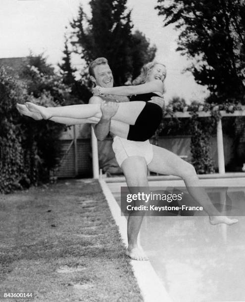 Michèle Morgan, dans les bras de son mari l'acteur William Marshall, saute dans la piscine de sa propriété à Beverly Hills, Californie, Etats-Unis en...