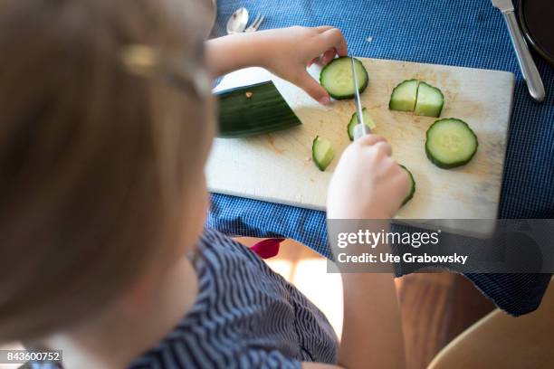 Bonn, Germany View from above on a five-year-old girl, who helps to prepare a meal and cuts a cucumber on August 07, 2017 in Bonn, Germany.