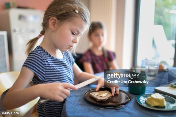 Bonn, Germany A five and a seven-year-old girl are having breakfast together. One girl is spreading bread with butter on August 07, 2017 in Bonn,...