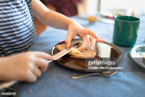 Bonn, Germany A child is having breakfast alone and spreads bread with butter on August 07, 2017 in Bonn, Germany.