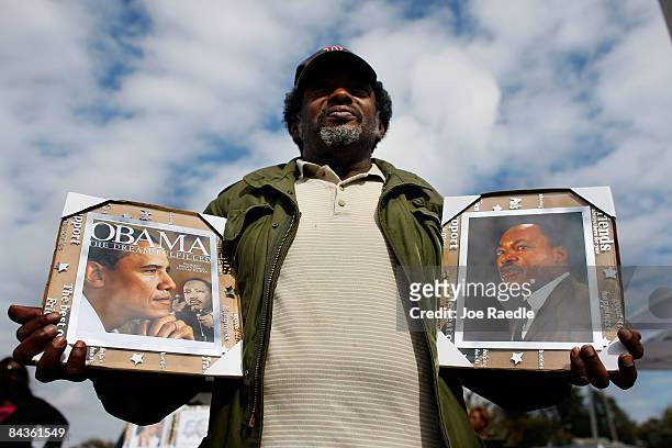 Rickie Baker holds pictures of President-elect Barack Obama and Dr. Martin Luther King, Jr. As he watches a parade pass by in honor of Dr. Martin...