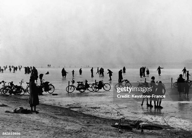 Des Hollandais patinent et font du vélo sur les rives gelées du Zuydersee le 20 janvier 1933 aux Pays-Bas.