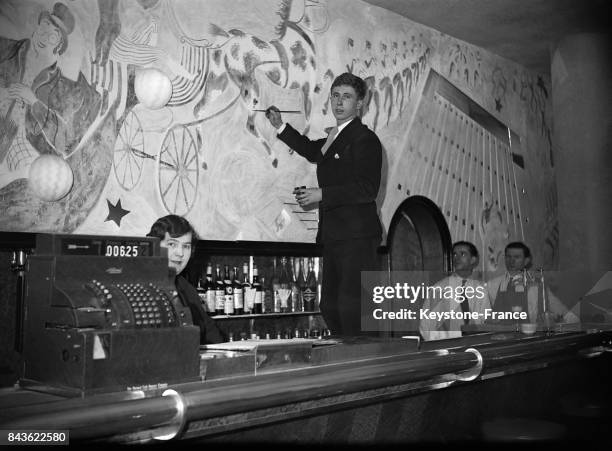 Le peintre Henry Mahé décorant le bar du nouveau cinéma de Montparnasse, à Paris, France le 28 décembre 1934.