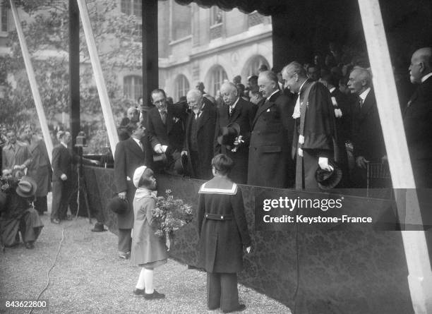 Au cours de la cérémonie, une petite fille offre un bouquet de fleurs au Président Lebrun, à ses côtés le ministre de l'Education nationale André...