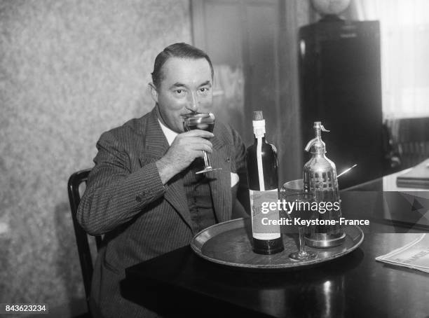 Un homme boit un verre de vin en apéritif dans un bistrot parisien, circa 1930 à Paris, France.