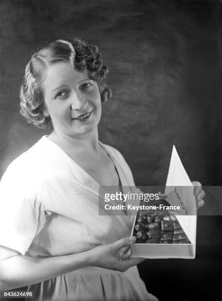 Jeune femme tenant une boîte de chocolats reprenant la couverture du livre lauréat du prix Goncourt 1932 'Les loups' de Guy Mazeline en France, en...