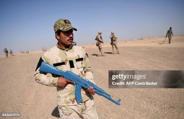 In this photograph taken on August 28 an Afghan National Army soldier holds a plastic gun while clearing a road during a training exercise to deal...