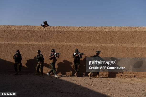 In this photograph taken on August 27, 2017 Afghan Commandos take positions during a combat training exercise at the Shorab Military Camp in Lashkar...