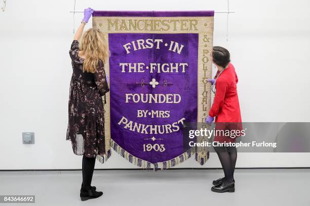 Conservators Jenny Van Enckevort and Kloe Rumsey inspect the Manchester suffragette banner hanging in the conservation department of Manchester...