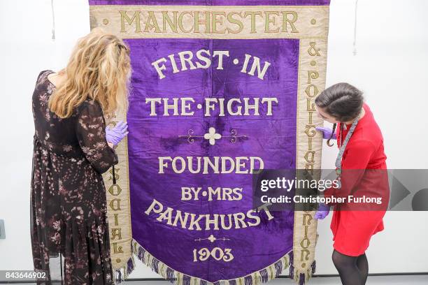 Conservators Jenny Van Enckevort and Kloe Rumsey inspect the Manchester suffragette banner hanging in the conservation department of Manchester...