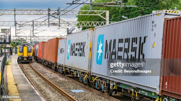 container train passes london midland commuter service in railway station - rail freight stock pictures, royalty-free photos & images