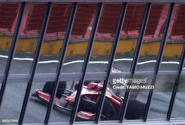 Window reflections show Finnish formula one driver Kimi Raikkonen as he pilots the new Ferrari F60 Formula One 2009 racing car during a test drive on...